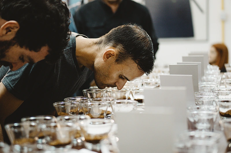 Homem analisando o aroma da amostra de café em treinamento para cafeterias