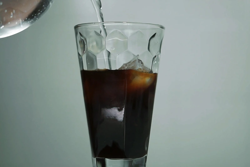 Acrescentando água gaseificada em copo de vidro para receita de coca de café
