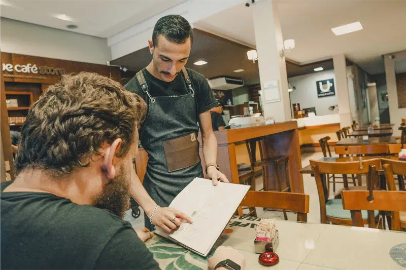 Barista apresentando o cardápio para um cliente na cafeteria