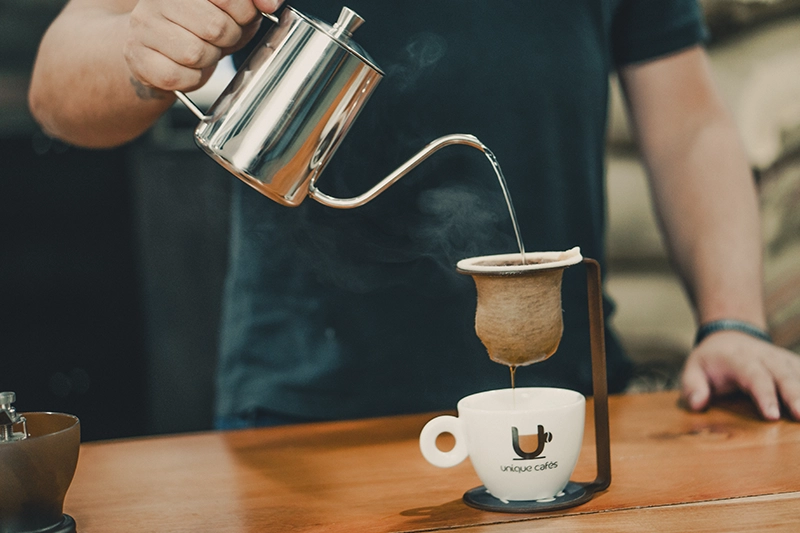 Barista servindo café especial coado sobre a mesa no coador de pano